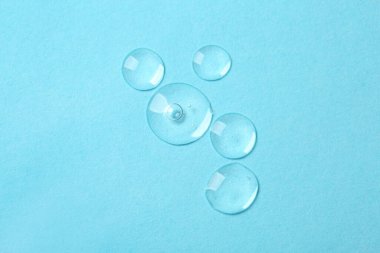 Açık mavi zemin üzerinde kozmetik serumu örnekleri, düz yatıyordu