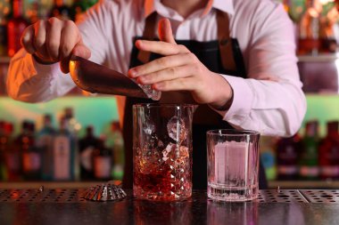 Alkolik kokteyl yapmak. Barmen bardaki bardağa buz küpleri ekliyor, yakın plan.