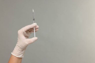 Doktor gri arka planda tıbbi şırınga tutuyor, yakın plan. Metin için boşluk