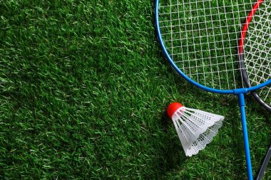 İki badminton raketi ve yeşil çimlerin üzerinde bir mekik çükü, üst görünümü metin için alan