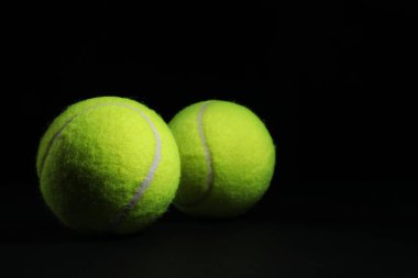 Siyah arka planda iki tenis topu, yakın plan. Metin için boşluk
