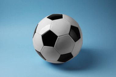 Açık mavi arka planda bir futbol topu. Spor malzemeleri.