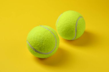 Sarı arka planda iki parlak tenis topu