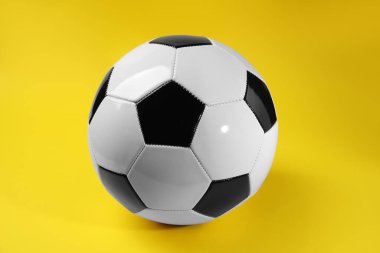 Sarı arka planda bir futbol topu. Spor malzemeleri.