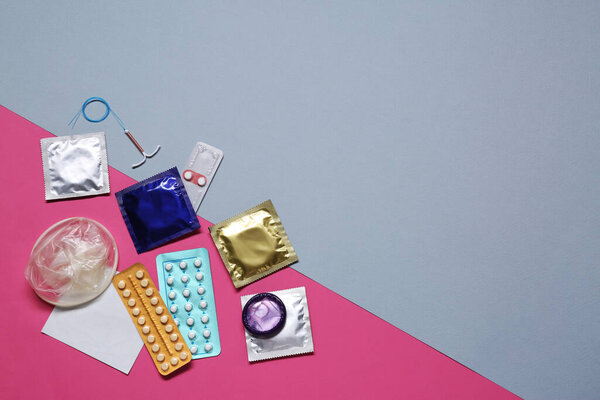 Противозачаточные таблетки, презервативы и внутриутробное устройство на цветном фоне, плоский лежал с пространством для текста. Различные методы контрацепции
