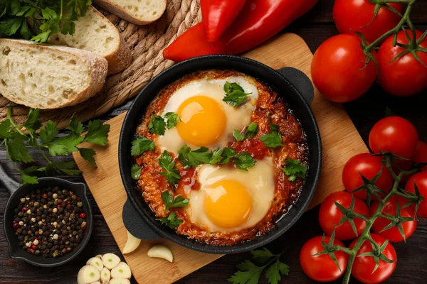 Düz kompozisyonda, ahşap masada lezzetli bir Shakshuka ile tavada yatıyordu.