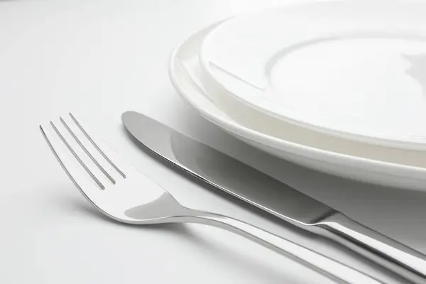 Καθαρά Πιάτα Πιρούνι Και Μαχαίρι Λευκό Φόντο Closeup — Φωτογραφία Αρχείου