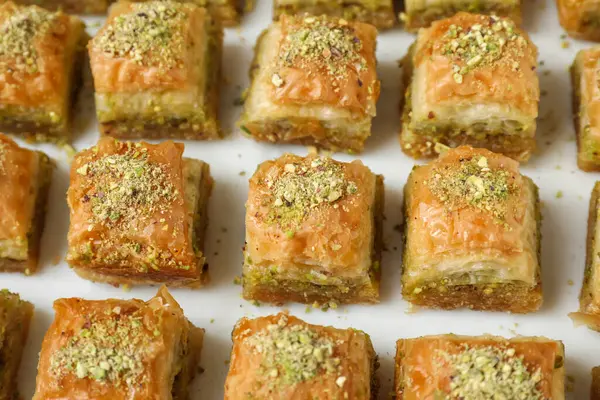 Delicious fresh baklava with chopped nuts on white table, above view. Eastern sweets