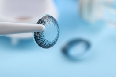 Açık mavi arkaplanda renkli lensli cımbızlar, yakın plan. Metin için boşluk