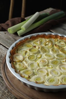 Lezzetli pırasalı turta ve çiğ saplar eski ahşap masada.