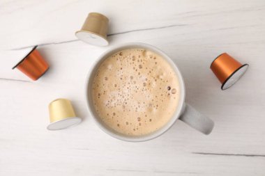 Bir fincan kahve ve kapsüller beyaz ahşap masada, düz yatıyordu.