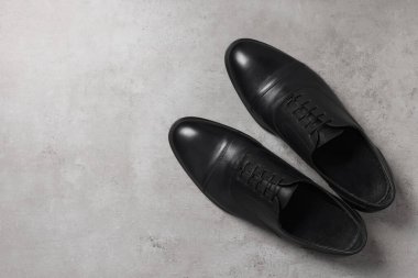 Açık gri yüzeyde bir çift siyah deri adam ayakkabısı, üst manzara. Metin için boşluk