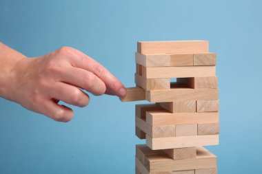 Açık mavi arka planda Jenga oynayan kadın, yakın plan