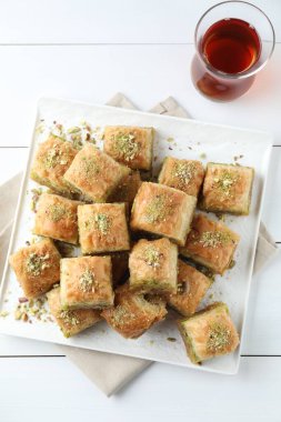 Lezzetli taze baklava, doğranmış fındık ve beyaz ahşap masa üzerinde çay, üst manzara. Doğu tatlıları