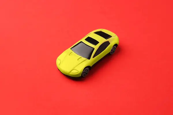 赤い背景にある黄色い車 子供のおもちゃ — ストック写真