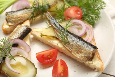 Lezzetli sandviçler, salatalık turşusu, soğan ve dereotu beyaz ahşap masada servis edilir.