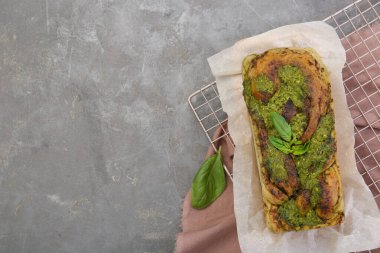 Gri masadaki fesleğenli taze pişmiş pesto ekmeği. Metin için boşluk