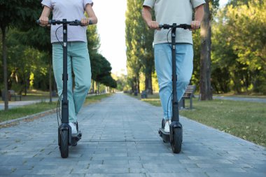 Parkta modern elektrikli scooter kullanan çift, yakın plan.