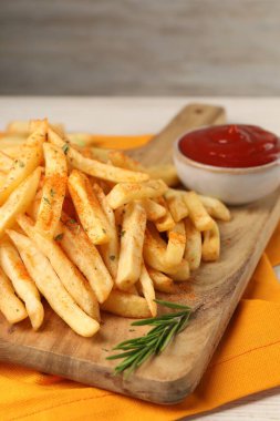 Lezzetli patates kızartması, beyaz ahşap masada sosla servis ediliyor, yakın plan.