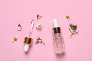 Bir şişe kozmetik serumu, pipet ve pembe arka planda güzel çiçekler.