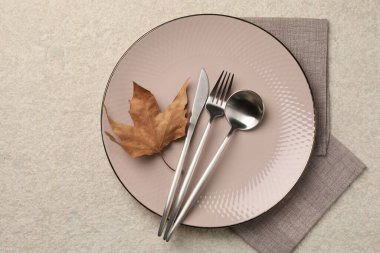 Işık yüzeyinde çatal bıçak ve kuru yaprak ile şık masa ayarları, üst görünüm