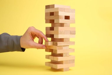 Sarı arka planda Jenga kulesi oynayan kadın, yakın plan.