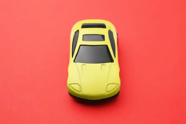 赤い背景にある黄色い車 子供のおもちゃ — ストック写真