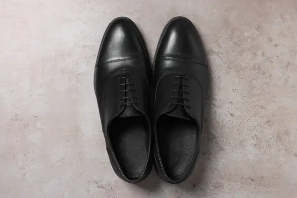 Pair of black leather men shoes on light grey surface, top view