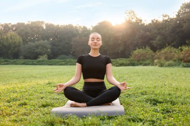 Güneşli bir günde dışarıda yoga yapan güzel bir kadın. Lotus pozu
