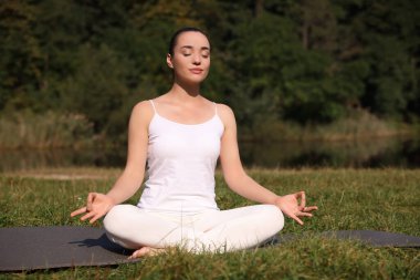 Güzel bir kadın dışarıda yoga yapıyor. Lotus pozu