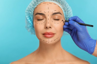 Açık mavi arkaplanda estetik ameliyat için kalem hazırlayan bir doktor, yakın plan.