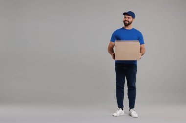 Gri arkaplan paketli mutlu genç kurye, metin için boşluk