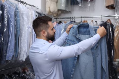 Kuru temizleme servisi. Kapalı alanda kot gömlek tutan bir işçi.