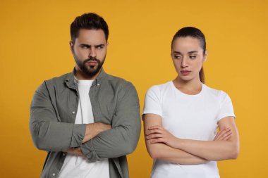 Turuncu arka planda çapraz kollu kızgın bir çift.