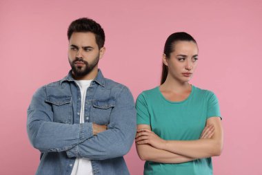Pembe arka planda çapraz kollu kızgın bir çift.