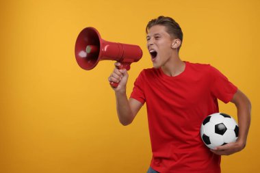 Turuncu arka planda megafonla bağıran futbol topu taraftarı. Metin için boşluk