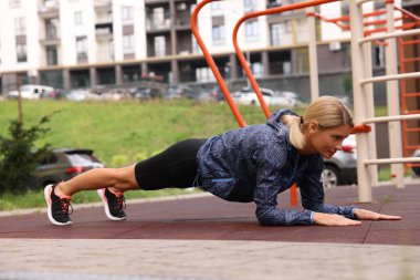 Açık spor salonunda tahta egzersizi yapan bir kadın, mesaj atmak için yer var.