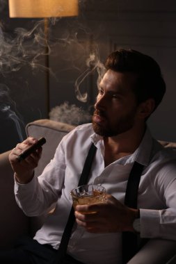 Evdeki koltukta puro içen yakışıklı bir adam.