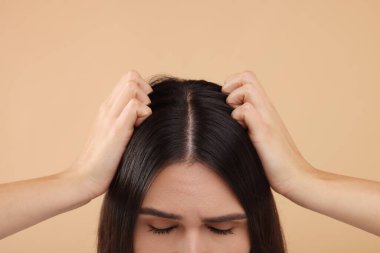 Bej arka planda sağlıklı saçlı bir kadın, yakın plan.