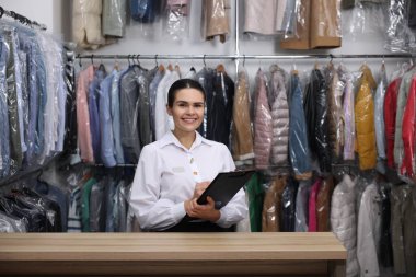 Kuru temizleme servisi. Kapalı alanda panosu olan mutlu bir işçi.