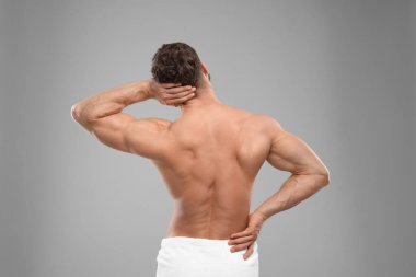 Man suffering from back and neck pain on grey background, back view clipart