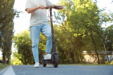 Parkta modern elektrikli scooter 'ı olan adam, yakın plan. Metin için boşluk