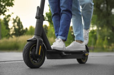 Parkta modern elektrikli scooter kullanan çift, yakın plan.