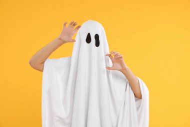 Sarı arka planda beyaz hayalet kostümlü kadın. Cadılar Bayramı