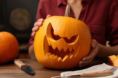 Ahşap masada oyulmuş balkabağı tutan kadın, yakın plan.