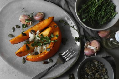 Peynir, mikroyeşillik, tohum ve sarımsak ile servis edilen fırınlanmış balkabağı dilimleri.