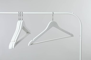 Boş giysiler açık gri arka planda askıda asılı duruyor