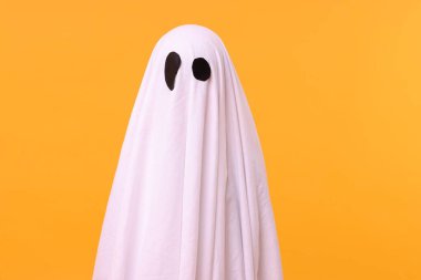 Turuncu arka planda beyaz hayalet kostümlü çocuk. Cadılar Bayramı