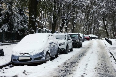 Kışın şehir caddesinde park etmiş arabalar.