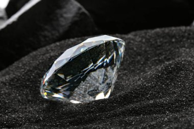 Dekoratif siyah kumlar üzerinde güzel parlak elmas, yakın plan.